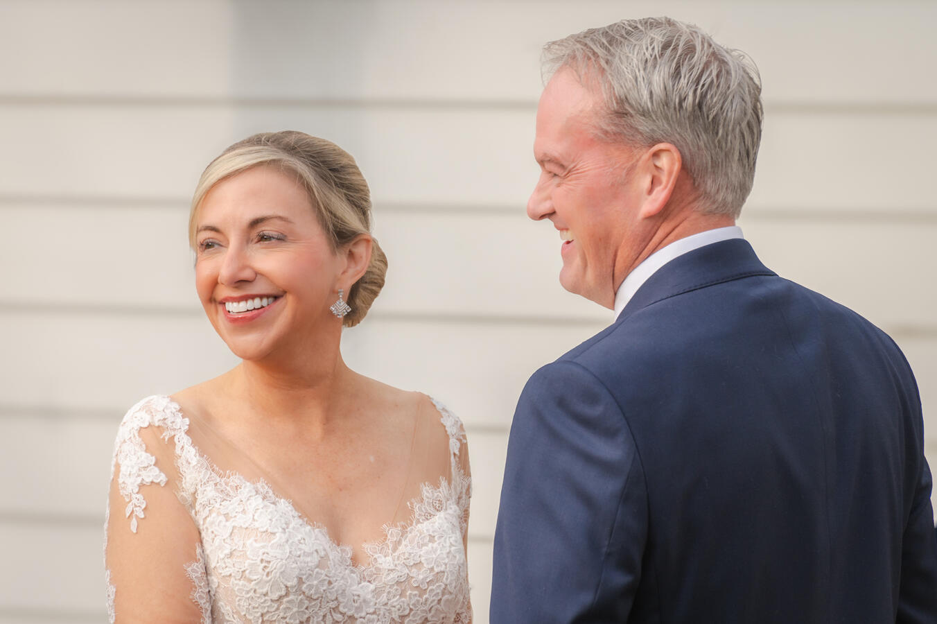 Two adults smile at the guests in their wedding.